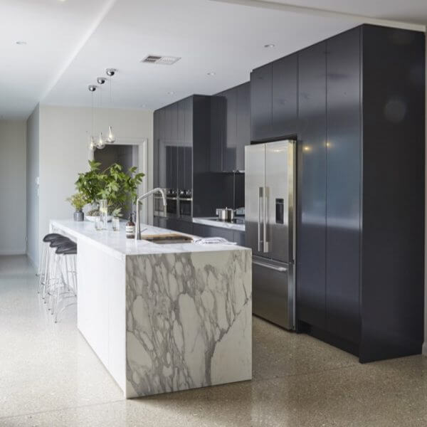 A contemporary kitchen with sleek marble counters and stylish black cabinets.