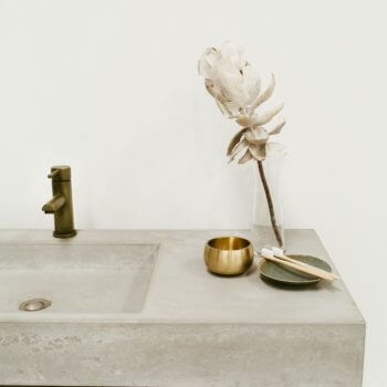 Cream marble bathroom basin and bench detail supported by brown metal beam